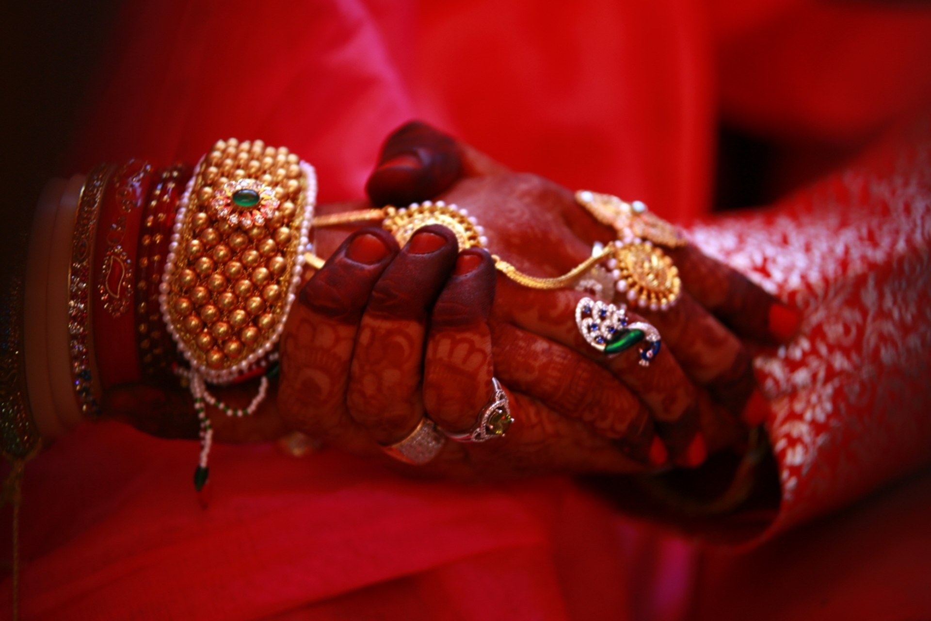 Bride's hands adorned with gold jewellery and henna